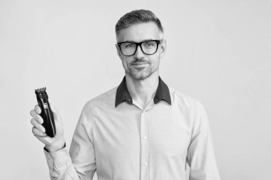 Elinde elektrikli tıraş makinesi olan bir adam. Olgun adam elektrikli jilet sunar. Saç bakım ve tıraş. Kişisel bakım ve günlük rutin işler. Berber dükkanı. Erkek için saç makası. Saç kesme makinesi olan adam..