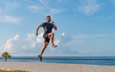 Spor yaşam tarzı. Yazın koşan sporcu. Spor koşuculuğu eğitimi. Sağlıklı yaşam tarzı ve günlük koşular. Koşan koşucu. Spor ve spor. Sahilde koşan adam, boşluğu kopyala.