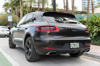 Miami, Florida, ABD - 02 Nisan 2025: siyah mat araba, köşe manzaralı. Porsche Macan 2015 çapraz arabası. Lüks araba Porsche Macan. Porsche Macan 'ın arabası dışarıda park edilmiş..