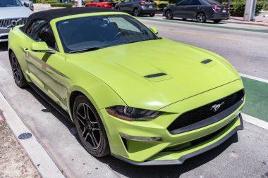 Miami, Florida, ABD - 21 Nisan 2025 Ford Mustang EcoBoost üstü açılabilir araba. Üstü açık spor araba Ford Mustang EcoBoost. Araba Ford Mustang park etmiş. Yeşil üstü açık araba, köşe manzaralı..