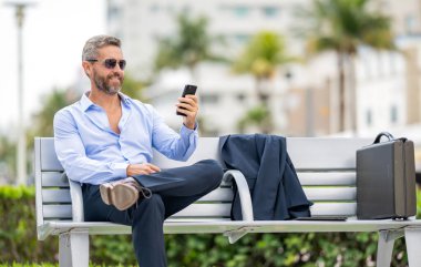 Sıradan bir iş adamı dışarıda telefonla konuşuyor. Telefon kullanan bir iş adamı. Adam telefonuyla bankta rahatlıyor. Telefonu olan İspanyol bir iş adamı. İş iletişimi. Boşluğu kopyala.