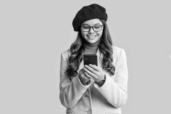 Autumn girl using phone isolated on yellow. Teen happy girl in autumn style beret and coat. Fall style. Girl chatting on phone. Adolescence generation. Adolescent girl with phone. Communication.