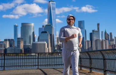 Koşucu uzun spor koşusunda. Koşucu dışarıda spor antrenmanında koşuyor. New York 'ta sabah sporu koşucusu. Sporcu adam koşuyor. Manhattan 'da koşan adam. New York 'lu. Büyük şehir rutini.