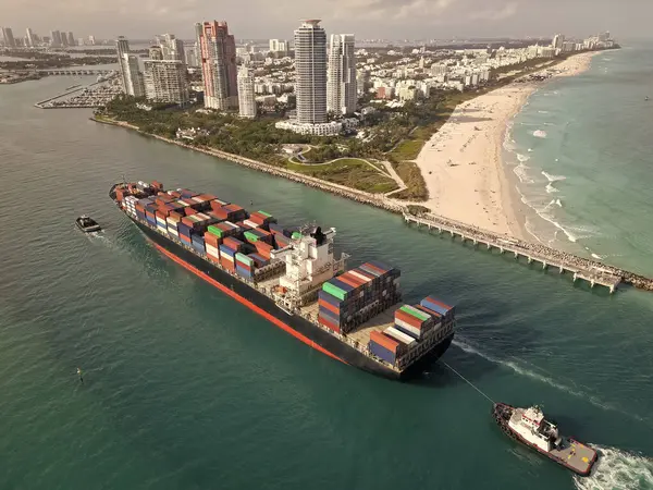 Yük konteynırı kargo gemisi. Kargo gemisi limandan ayrılıyor. Konteyner gemisi. İhraç ve ithalat. Kargo işi. Miami Limanı. Miami 'de konteynırlı kargo gemisi, hava manzaralı. Devasa çelik gövde..