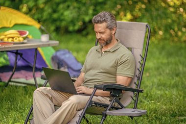Yaz kampı. Kampta dizüstü bilgisayarda daktilo yazan bir iş adamı. İnternette çalışan bir iş adamı. Serbest çalışan bir iş adamı. Dışarıda çalışan bir iş adamı. Kumanda sırasında piknik yapan bir adam..