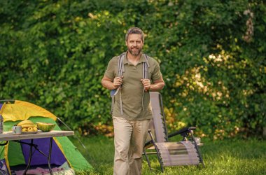 Yaz kampı ve doğa tatili. Yaz kampındaki adam. Kamp macerası. Yürüyüş konsepti. Kamp çadırı. Ormanda çadırlı sırt çantalı bir adam. Yaz günü doğa yürüyüşçüsü..