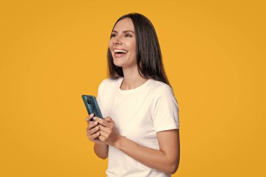 Millennial gülen kadın telefonda blog yazıyor ya da sarıda izole edilmiş akıllı telefondan iletişim kuruyor..