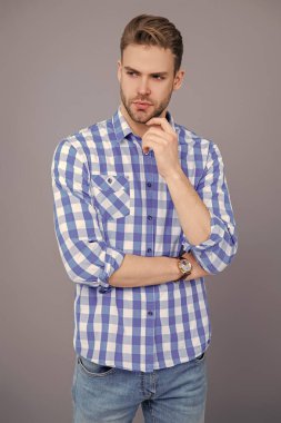 Kareli gömlek giyen milenyum adamı. Milenyum erkeğinin gündelik tarzı. Sıradan tişörtlü bir adamın portresi. Tıraşsız adamın zarif portresi. Gri yolda izole edilmiş bir adam. Günlük kıyafet..