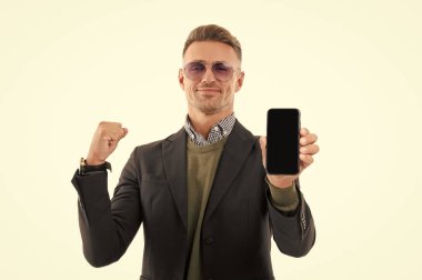 İş uygulamasının reklamı. Olgun iş adamı telefon ekranını sunuyor. İş adamı, telefonun beyazda izole olduğunu gösteriyor. Adam yeni iş telefonu uygulamasını gösteriyor. Başarıyı ifade etmek. Ürünü sunuyorum..