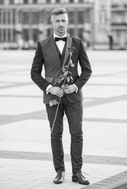 Siyah smokinli zarif bir adam. Smokin papyon takan adam dışarıda. Kırmızı güllü yakışıklı smokin adam. tam uzunluk.