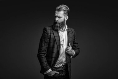 Bespoke takımı. Özel dikim erkek giysisi giymiş sakallı adam. Özel dikim kıyafet giyen bir iş adamı. Şık takım elbiseli bir iş adamı. Resmi terzilik kıyafeti. Erkek giyim kuşamı. Bohem stili.