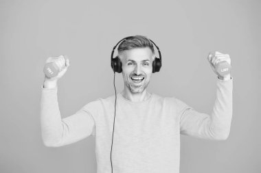 Atletik egzersiz için müzik. Güçlü bir sporcu. Olgun bir adam mavi üzerinde spor eğitimi yapar. Halterli ve dambılı bir sporcu. Müzikli spor salonu. Spor salonu. Atletik performans.