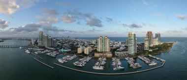 Miami silueti ve Biscayne Körfezi Panoraması. Kıyı gökdelenleri olan panoramik şehir manzarası. Miami Beach 'in yukarıdan manzarası. Drone Fisher Adası 'nı ve limanı ele geçirdi.