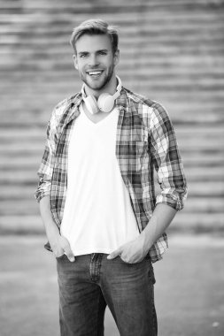 Öğrenci hayatı. Öğrenci adamın kulaklığında müzik var. Milenyum kuşağı sesi dinler. Müzik aşığı yaşam tarzı. Dışarıda müzik kulaklığı takan milenyum adamı. Modern yaşam tarzı. Minimalist estetik.