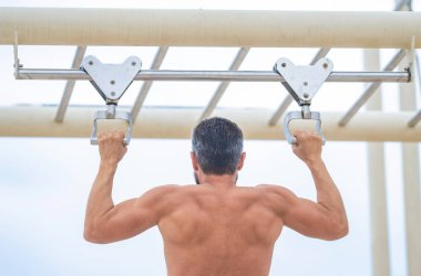 Güçlü bir atlet. Adam yanaşıyor. Güçlü sırt kası olan kaslı bir sporcu. Spor barfiks egzersizi. Spor eğitimi. Sporcu adam egzersiz yapıyor. Erkek kaslı sırt sporcusu dışarıda spor yapıyor..