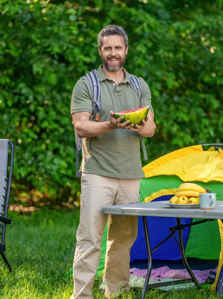 Yaz kampında karpuzlu bir adam. Yaz günü doğa yürüyüşçüsü. Kamp ve doğa pikniği. Adam kampı. Karpuz kampı pikniği. Lezzetli sağlıklı yiyecekler. Kampta taze yiyecek var..