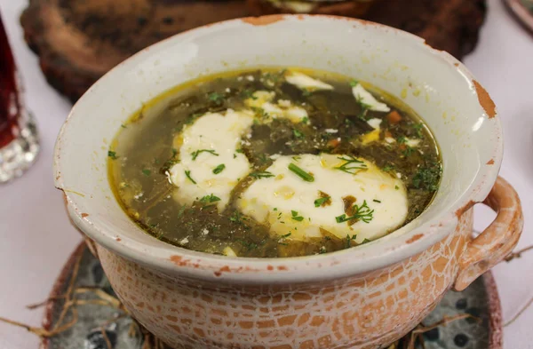 Green soup with sour cream in a clay pot. Ukrainian green borscht. Traditional cuisine.