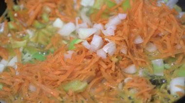  Doğranmış havuç, soğan ve sebze biberleri ayçiçeği yağında bir tavada pişirilir..