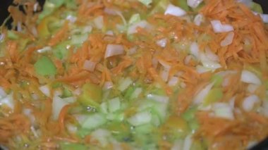  Doğranmış havuç, soğan ve sebze biberleri ayçiçeği yağında bir tavada pişirilir..