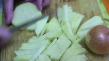  Evde kızartma yapmak için patatesleri tahtanın üzerinde kesiyorlar..