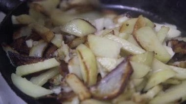  Aşçı kızartma tavasında soğanlı ve sarımsaklı patatesleri karıştırır.