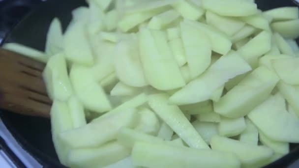 木製のスプーンがフライパンに生のジャガイモのみじん切りをかき混ぜてクローズアップ — ストック動画