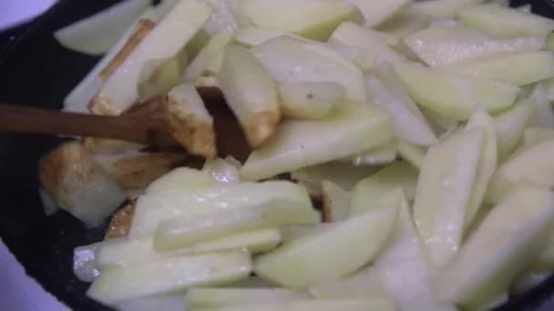 一只木制勺子搅动着煎锅里仍在切碎的生土豆 这是特写镜头 — 图库视频影像