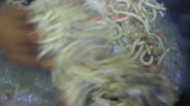 Ahşap bir kaşık sosu makarna ve tavukla karıştırır, yakın plan..