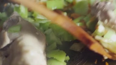  Kızartma tavasında doğranmış sebzeleri etle karıştırmak, yakın plan..