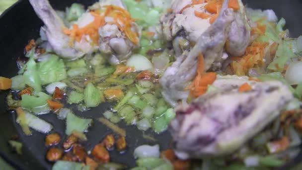 숟가락으로 프라이팬에 야채를 잘게썬 닭고기 날개를 흔들며 프라이팬을 클로즈업 — 비디오
