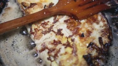 Soğanlı ve peynirli tavuk yumurtası tavada kızartılır, tahta kaşığın yanında..