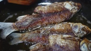Tahta kaşık balığı kızartma tavasında döndürür, yakın plan..