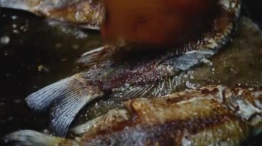 Tahta kaşık balığı kızartma tavasında kabukla hareket ettirir, yakın plan.