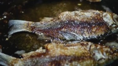 kaşık kızartma tavasında çarmıha gerilmiş balık çevirir