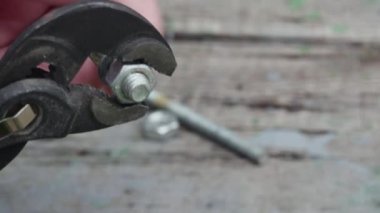 Bir el, masanın üzerinde ayarlanabilir anahtarı olan bir somundan cıvata açar. Yakın plan.