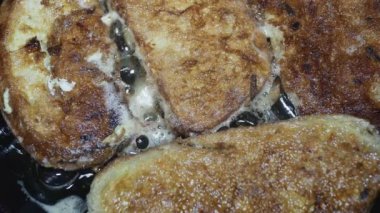 Tahta kaşık tavadan yumurtalara batırılmış bir kabukla kızarmış ekmeği kaldırır.