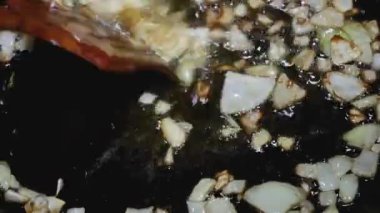 Tahta kaşık, ayçiçeği yağında kızartılmış doğranmış soğanı karıştırır..