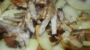 Kızartma tavasında kesilmiş pençeleri olan tavuk bacaklı kızarmış patates, makro.