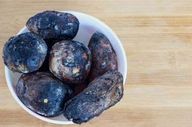 Tahta bir tabakta kül içinde fırında patates..