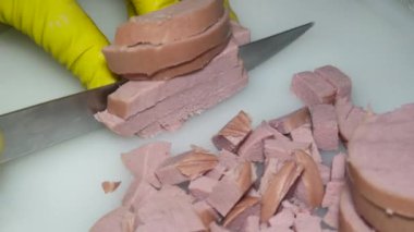 Bıçaklı bir el haşlanmış sosisi parçalara ayırır.