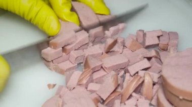  Bıçaklı bir el haşlanmış sosisi parçalara ayırır, salata için.