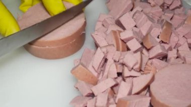  Aşçının eli bıçakla haşlanmış sosisi keser, salata için.