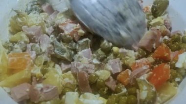 Bir kaşık sosisli patates salatası ve mayonezli salatalık turşusu karıştırır, (Olivier salatası)