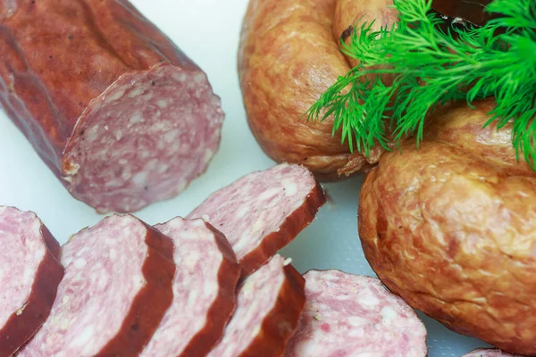  two types of sausages on a white cutting board with a sprig of dill.
