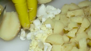 a cook's hand with a knife cuts boiled potatoes, on a cutting board, close-up.