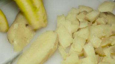 cook's hand with a knife cuts boiled potatoes, close-up.
