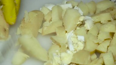 a cook's hand with a knife cuts boiled potatoes, on a cutting board.