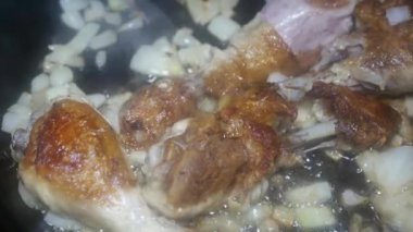 appetizing chicken drumsticks with onions in a frying pan, top view
