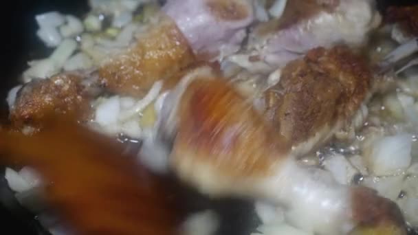 Wooden Spoon Stirs Chicken Drumsticks Appetizing Crust Onions Frying Pan — Stockvideo