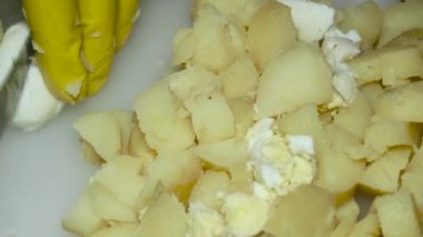 the cook's hand cuts the boiled egg next to the boiled potatoes, close-up.